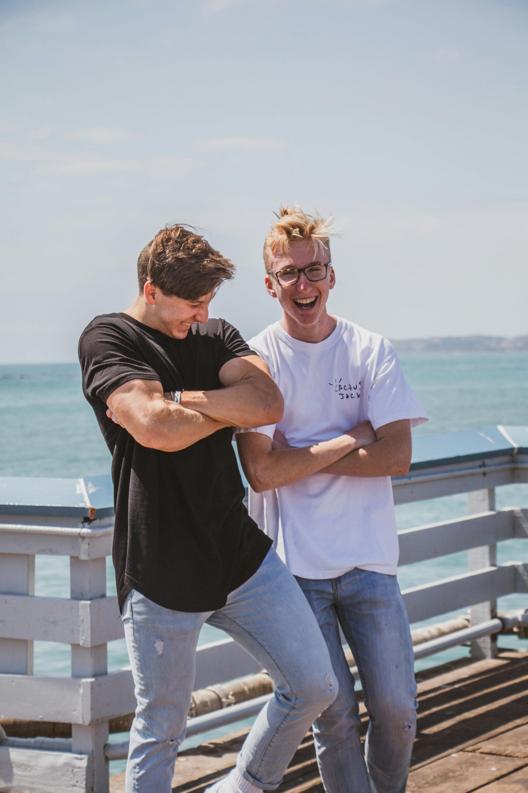 pexels-photo-2777719-2777719 Two men laughing and posing outdoors against a sea backdrop, exuding stylish vibes.